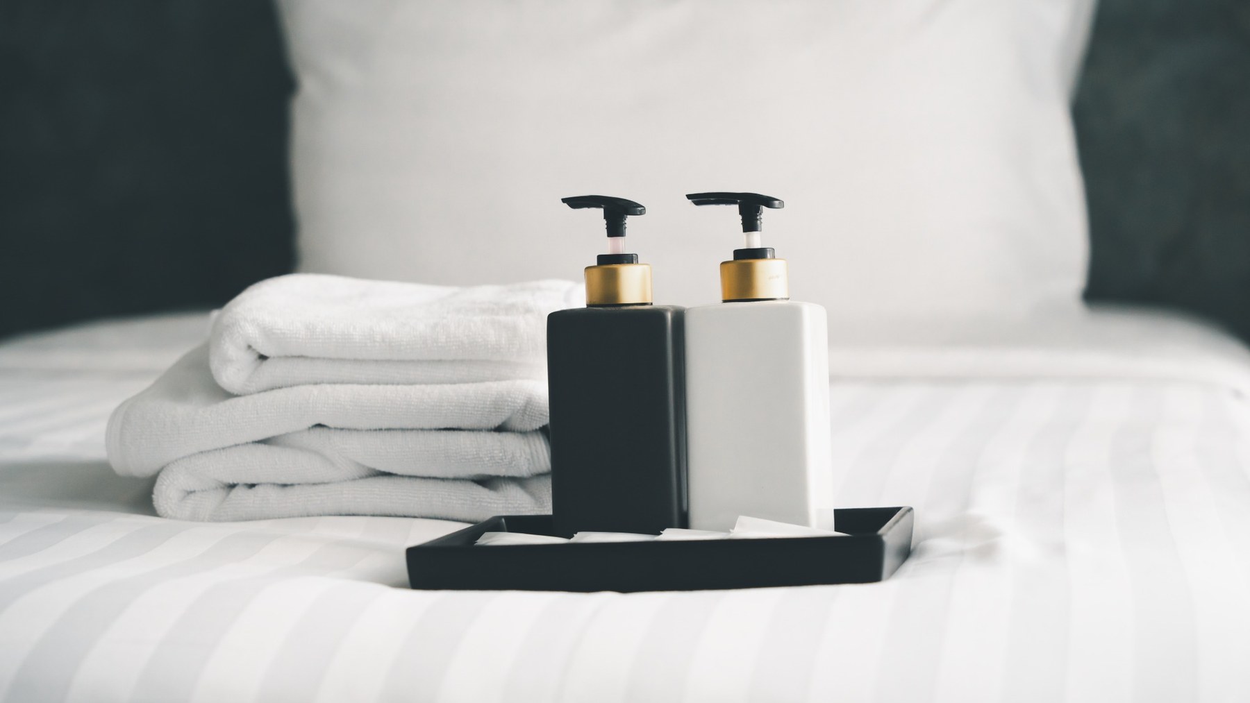 Hotel-Amenities mit Pflegeprodukten und Handtüchern auf einem Hotelbett
